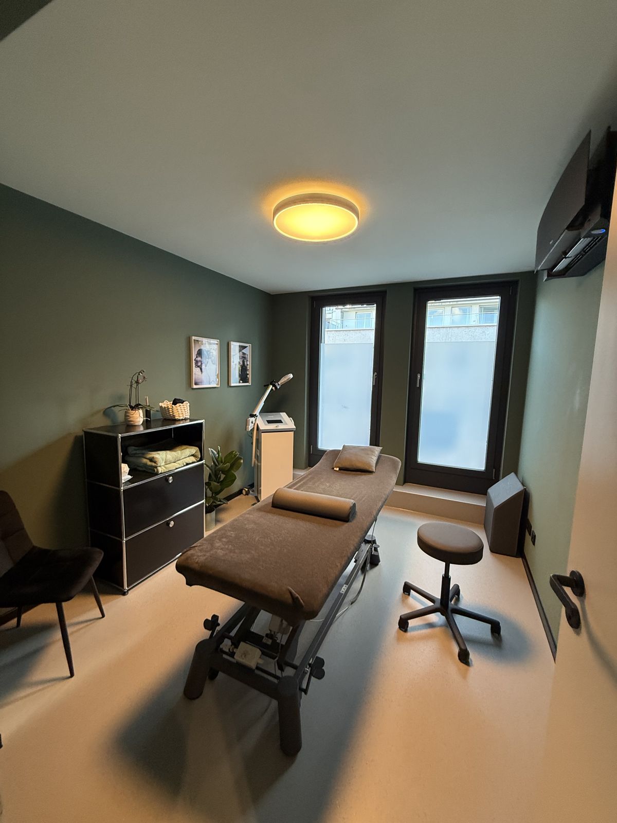 Behandlungsraum der PhysioNova Physiotherapie Frankfurt mit Therapieliege und großen Fenstern